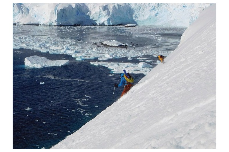 dos esquiadores bajando una fuerte pendiente con el mar lleno de hielo al fondo